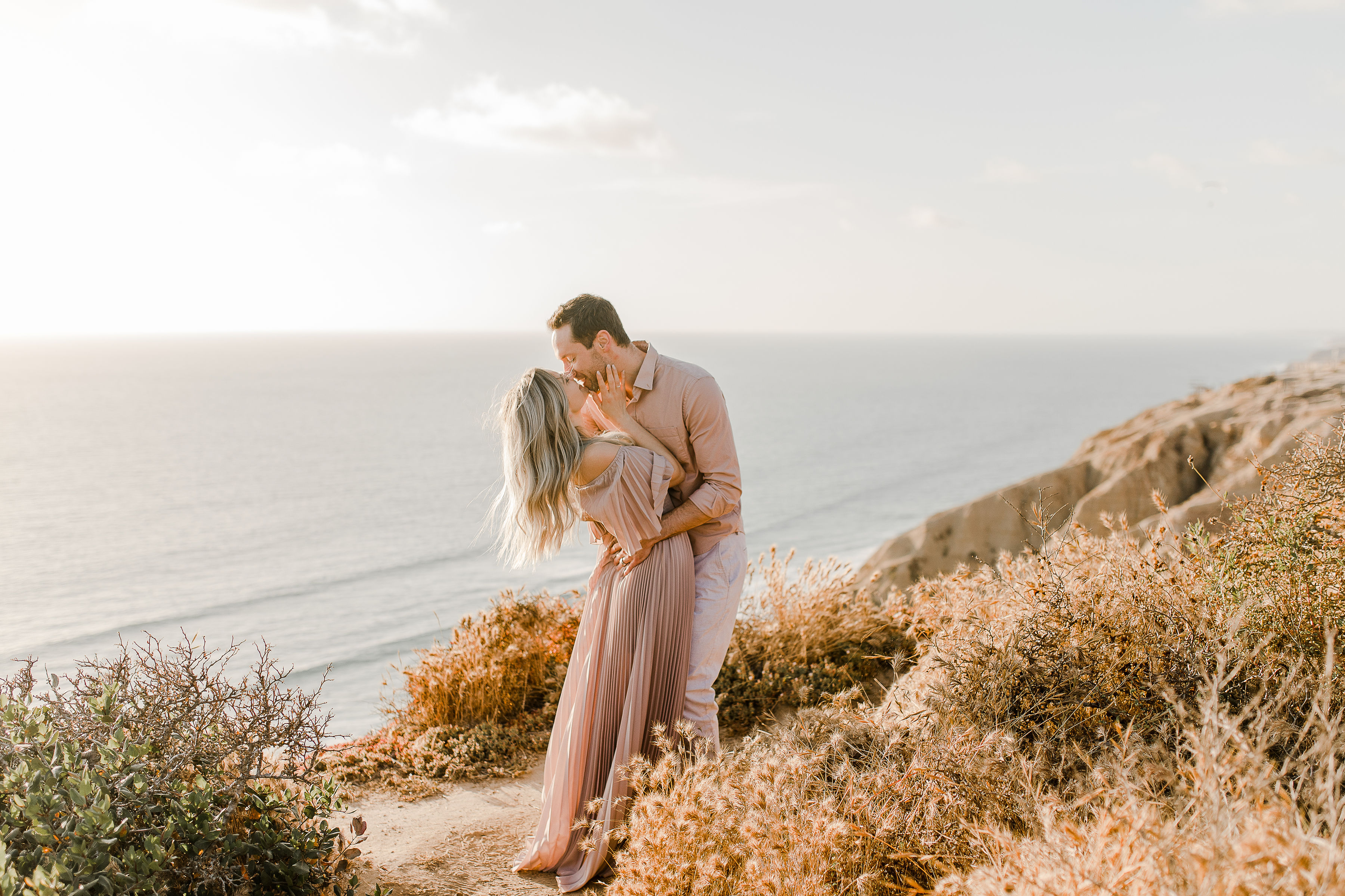 bride and groom kissing with the ocean sunset in the backdrop during their Torrey Pines Gliderport Couples Session