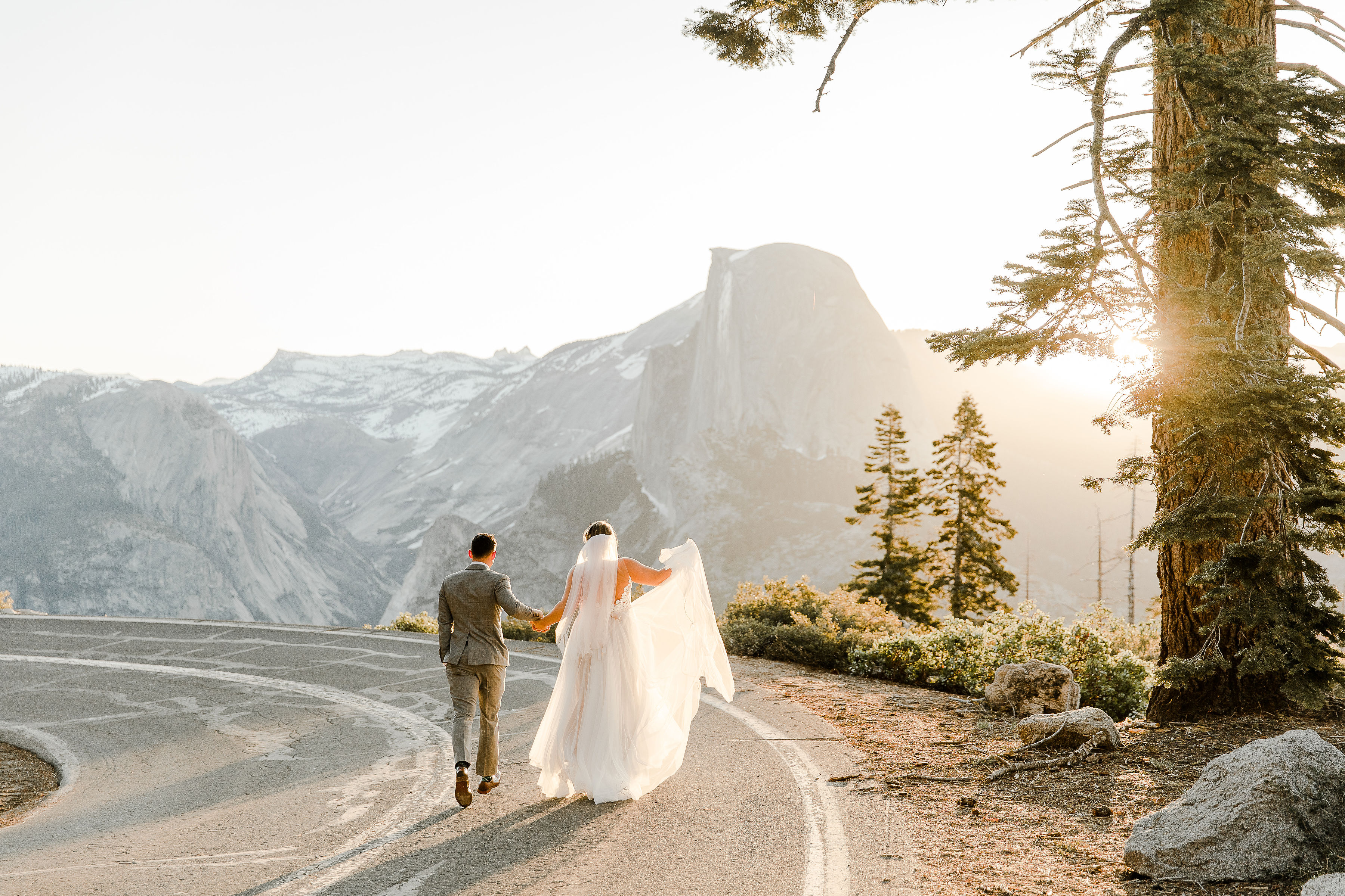 bride and groom walking on road in yosemite national park with half dome in the background