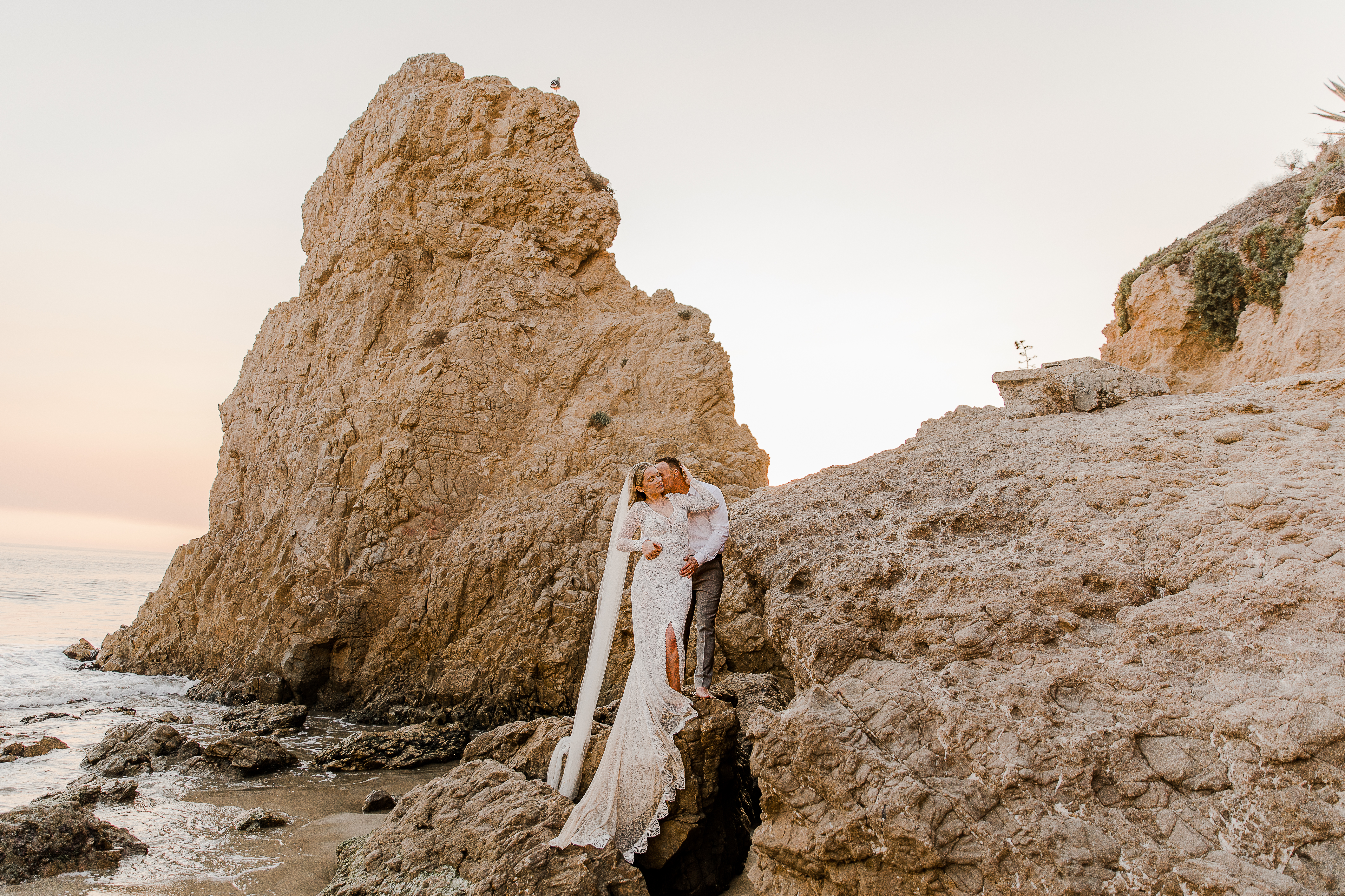bride and groom climb on top of a rock during their el matador beach elopement